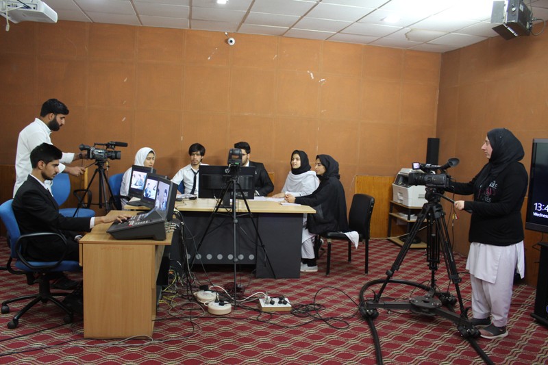 Students holding mock news discussion at department studio.